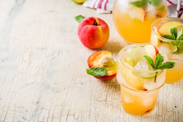 Peach and lime lemonade, mojito cocktail with fresh fruit garnish