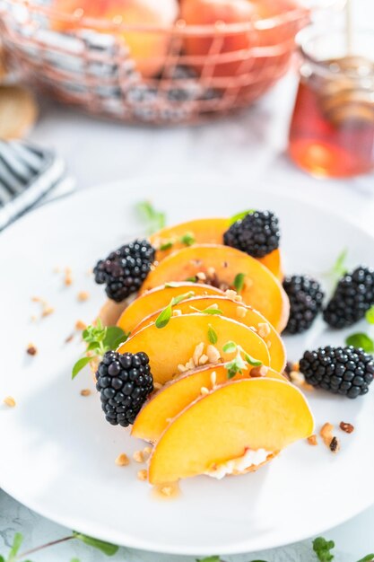 Peach ricotta toast garnished with blackberries on a white plate.