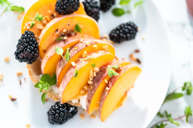 Peach ricotta toast garnished with blackberries on a white plate.