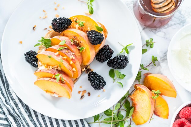 Peach ricotta toast garnished with blackberries on a white plate.