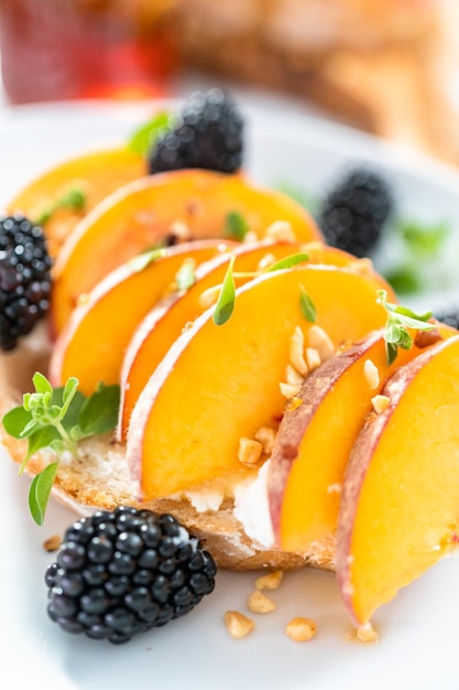 Peach ricotta toast garnished with blackberries on a white plate.