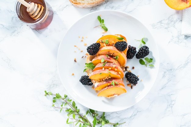 Peach ricotta toast garnished with blackberries on a white plate.