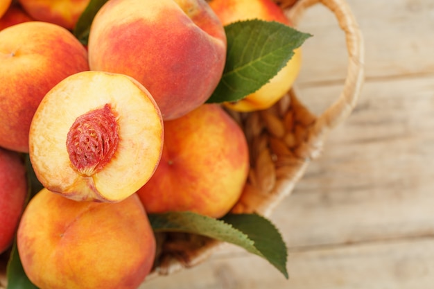 Peaches in a basket on a wooden with a slice of sliced juicy peach with a stone