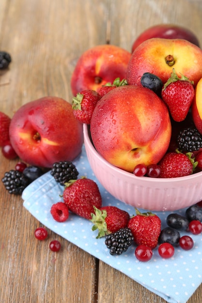 Peaches and berries in bowl on table closeup