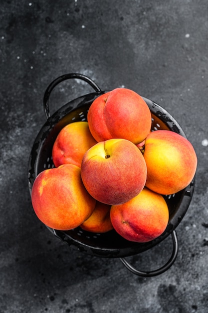 Peaches fruit in a black colander on the table