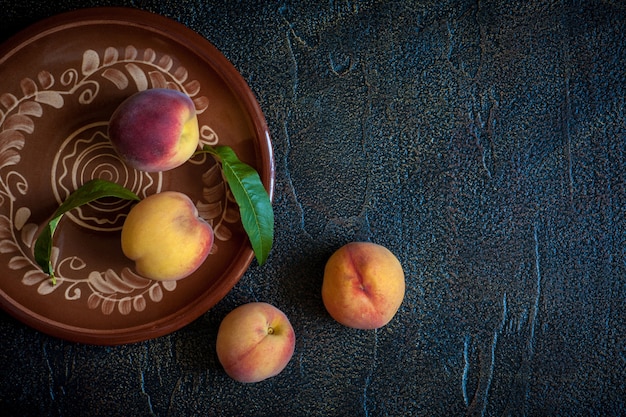 Персики на тарелке на черном столе