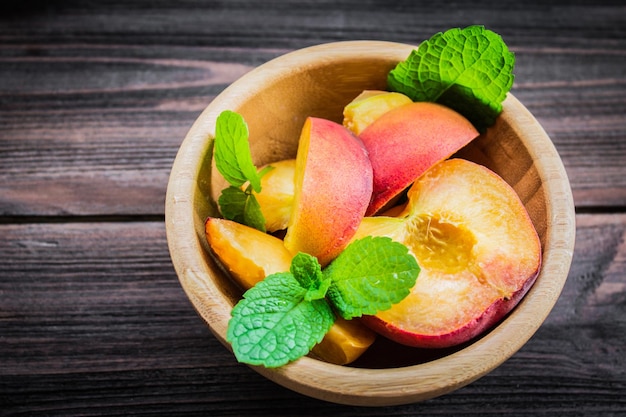 Peaches in a plate on a wooden background