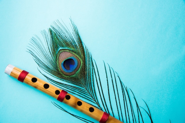 Photo peacock feather and bamboo flute over colourful background