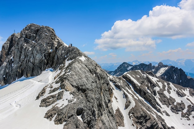 На вершине Дахштайн и с видом на альпийские горы. Национальный парк в Австрии, Европе. Голубое и пасмурное небо в летний день