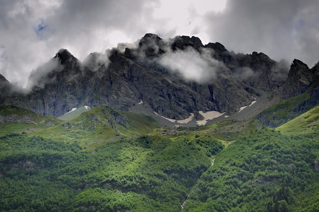 雲と空を背景に氷河のある山の頂上。白人の尾根、ロシア。