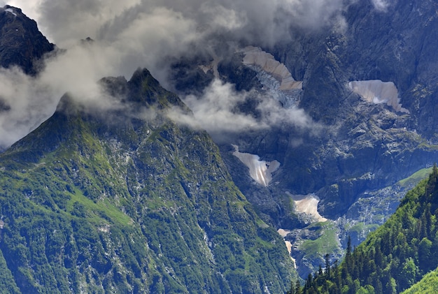 雲と空を背景に氷河のある山の頂上。白人の尾根、ロシア。