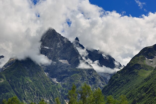 Peak of the mountain with glaciers against the surface of clouds and sky