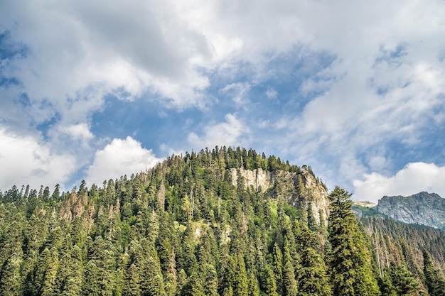 Peaks of magnificent rocks located against bright cloudy sky on sunny day in nature