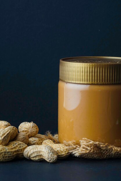 Photo peanut butter in the bottle and groundnut over the black background