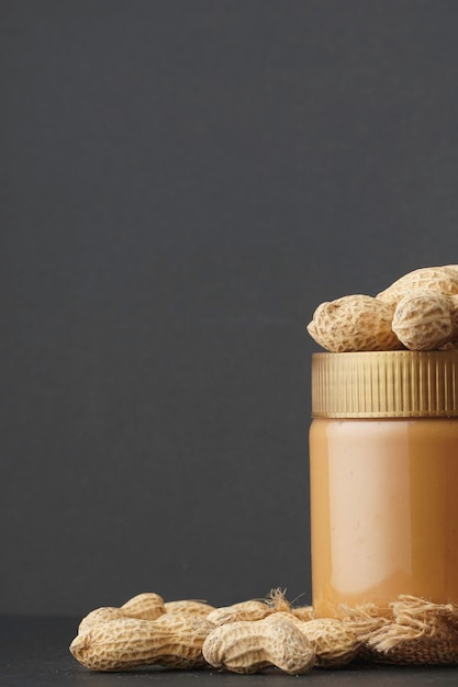 Photo peanut butter in the bottle and groundnut over the black background