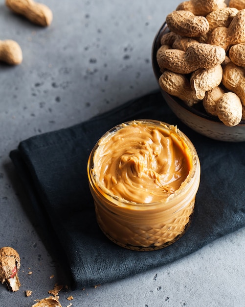 Peanut butter close-up, peanuts in shell in a bowl on a gray surface