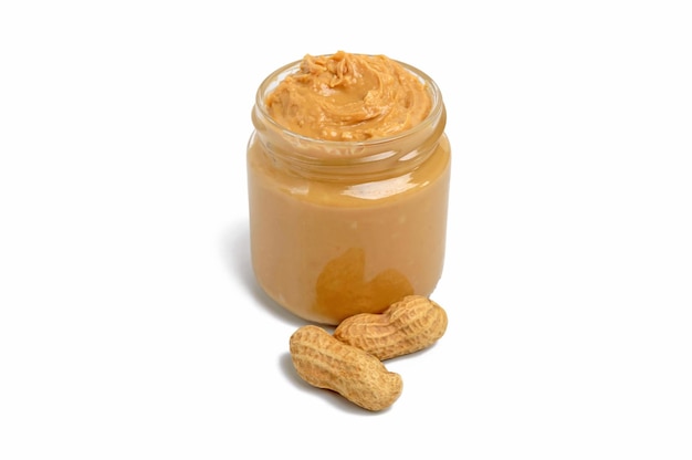 Peanut butter in a glass jar with peanuts isolated on white background.  A traditional product of American cuisine.