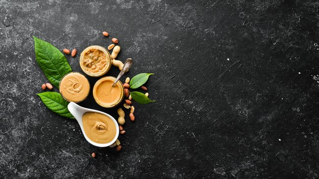 Peanut butter and nuts on a black stone background Healthy food Top view