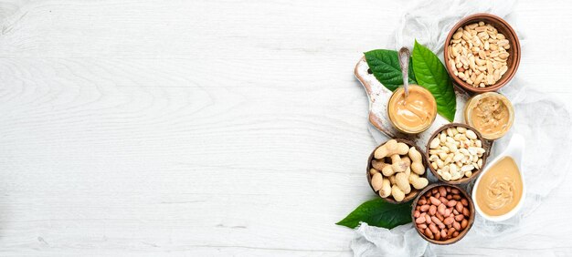 Peanut butter and nuts on a white wooden background Free space for your text