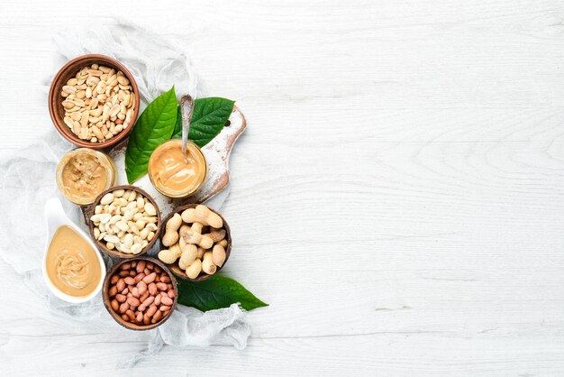 Peanut butter and nuts on a white wooden background Free space for your text