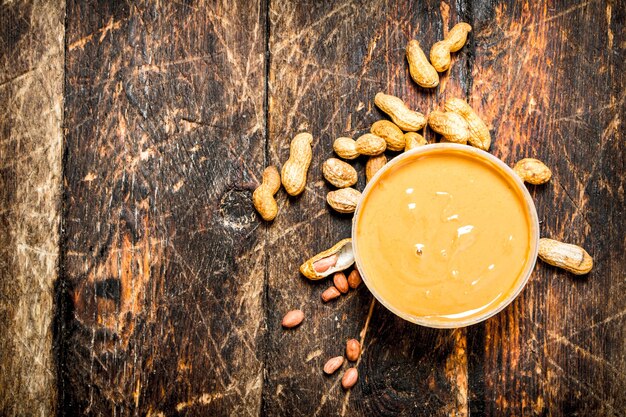 Peanut butter with nuts. On wooden background.