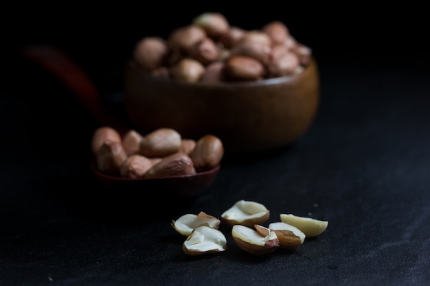 Peanut on Cup made of wood and spoon on black background