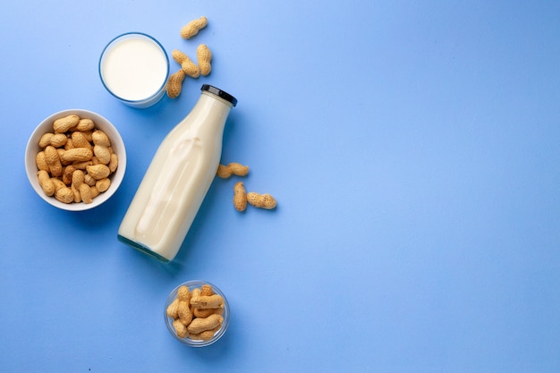 Peanut non dairy milk in glass bottle with bowl of peanuts