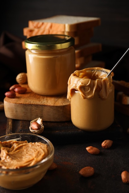 Foto peanut paste in een glazen pot op een donkere achtergrond