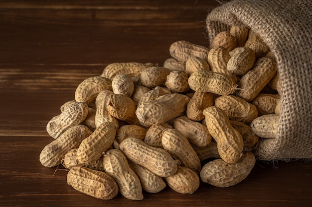 Peanut in sack bag on wooden background.