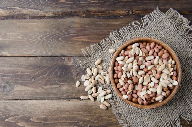 Peanuts and almonds on wooden bowl and burlap