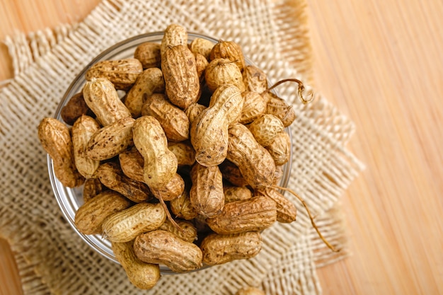 Peanuts in bowl on the wooden background.