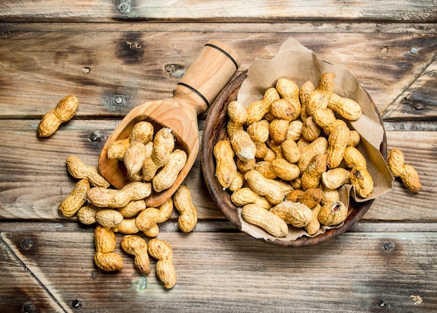 Peanuts in a bowl and a wooden scoop