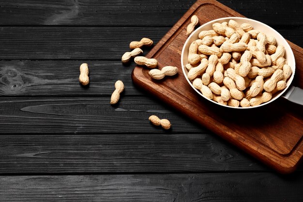 Peanuts in a pan on a black wooden background