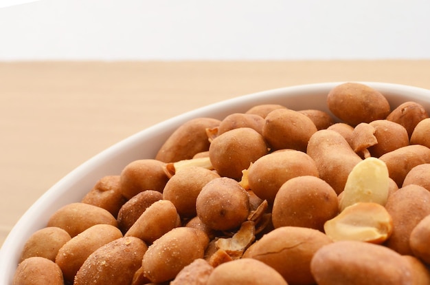 Peanuts in shell in white bowl on wooden table. Traditional peanut from Brazil.