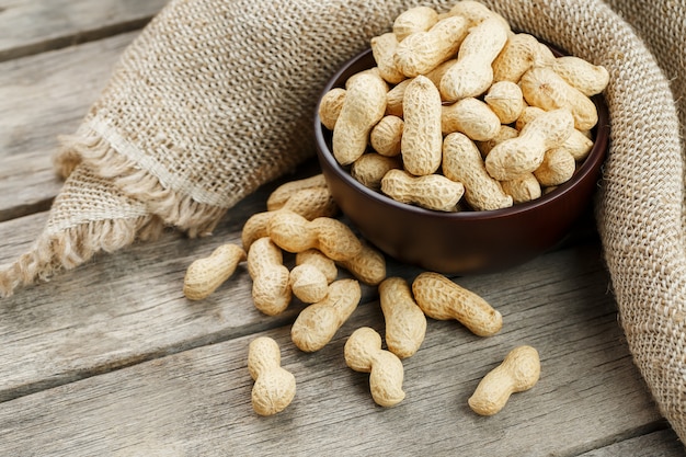 Peanuts in the shell, in a wooden cup on the table.