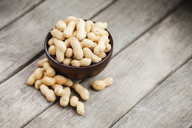 Peanuts in the shell, in a wooden cup on the table.