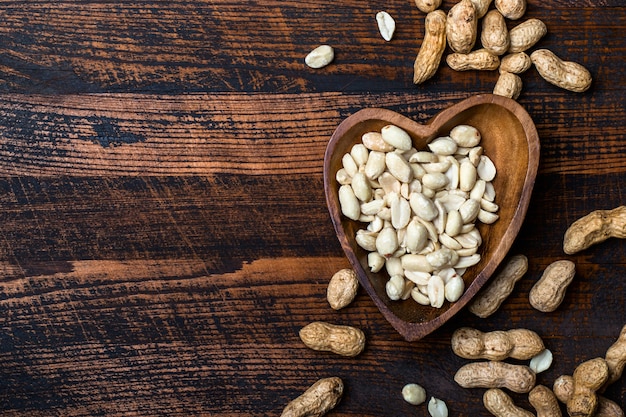 Peanuts snack in bowl on dark background.