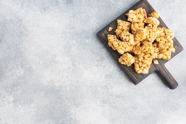 Peanuts in sugar glazed, oriental sweetness of brittle. Kozinaks are broken into pieces on a wooden Board, copy space. top view