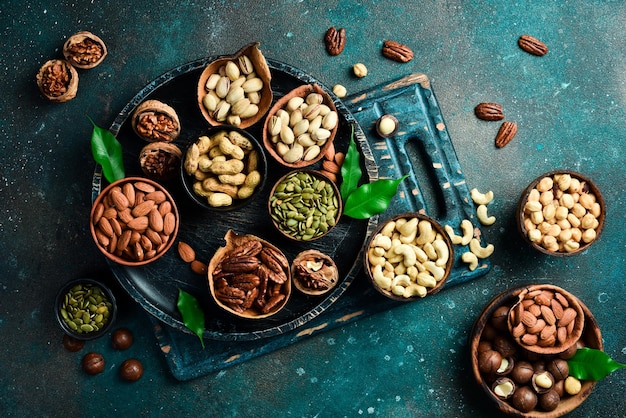 Photo peanuts walnuts almonds hazelnuts and cashews mixed together in wooden bowls top view on a dark background