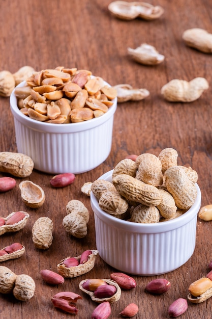 peanuts in a white bowl rests on an old wooden table.