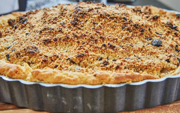 Photo pear pie and chocolate chips in metal pan after baking in the oven. french gourmet cuisine.