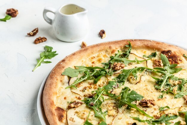 Photo pear pizza with blue cheese, walnut and arugula. delicious pizza. top view