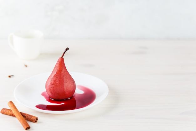 Pear in red wine on a white plate