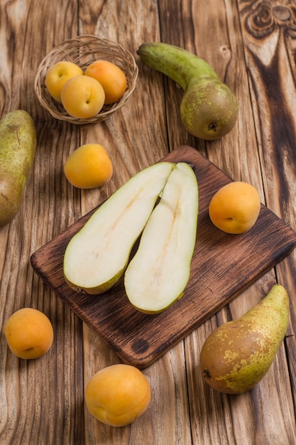 Pear and ripe apricots on a wooden table.