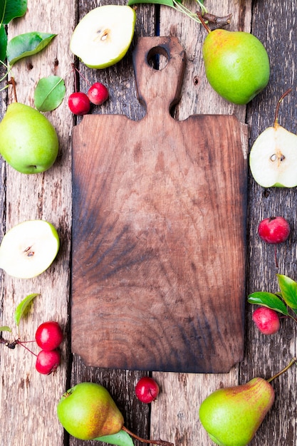 Pear and small apple around empty cutting board
