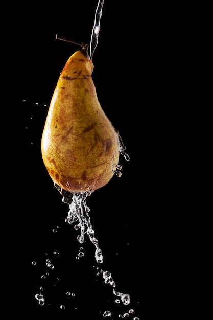 Pear with falling drops of water on a dark background