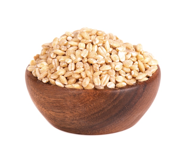 Pearl barley grains in wooden bowl, isolated on white background. Barley seed close up.