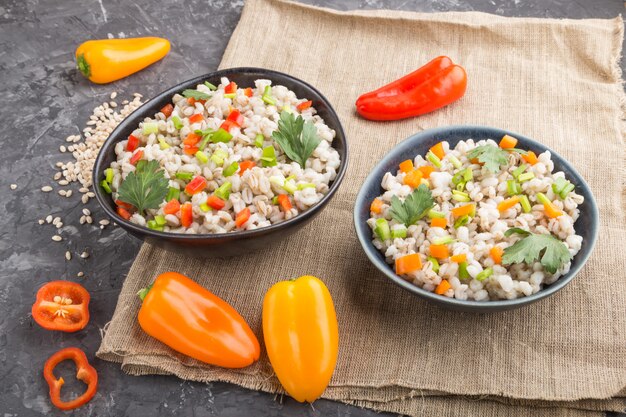 Pearl barley porridge with vegetables in blue ceramic bowls.  Side view, close up.