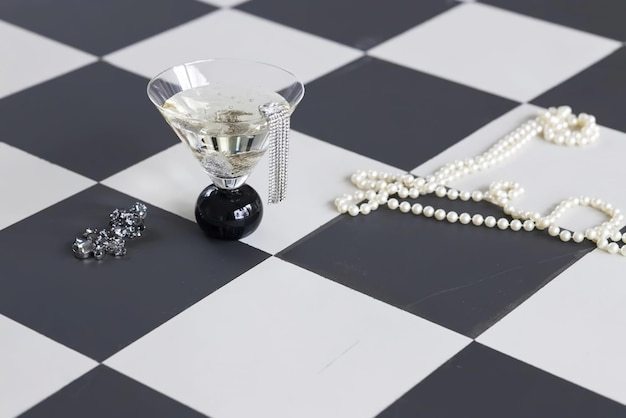 Pearl beads and glass with jewelry on the chess board