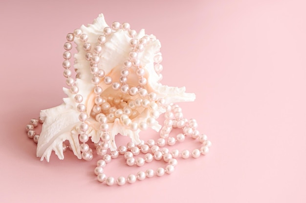 Pearl beads on pastel pink background with copy space